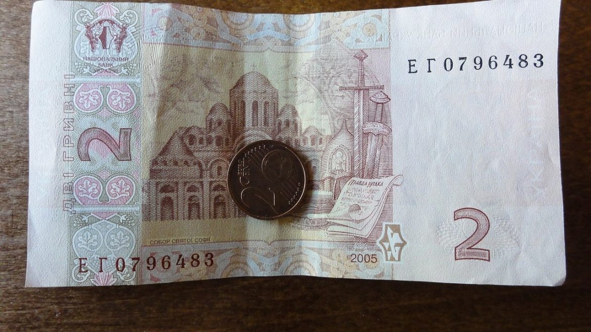 Банкнота 2 гривні і монета на дерев’яному столі